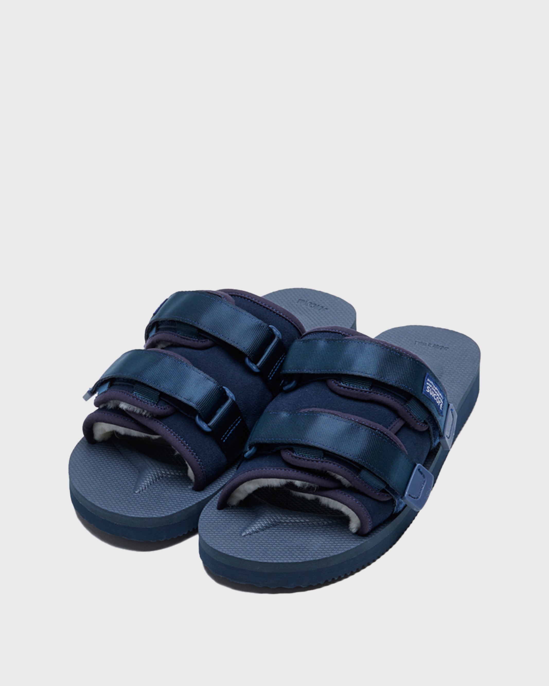 SUICOKE MOTO-Mab suede slides with navy midsole and sole, navy suede upper and shearling inside with navy piping and nylon straps and end tabs, and logo patch. From Fall/Winter 2021 collection on SUICOKE Official US & Canada Webstore.