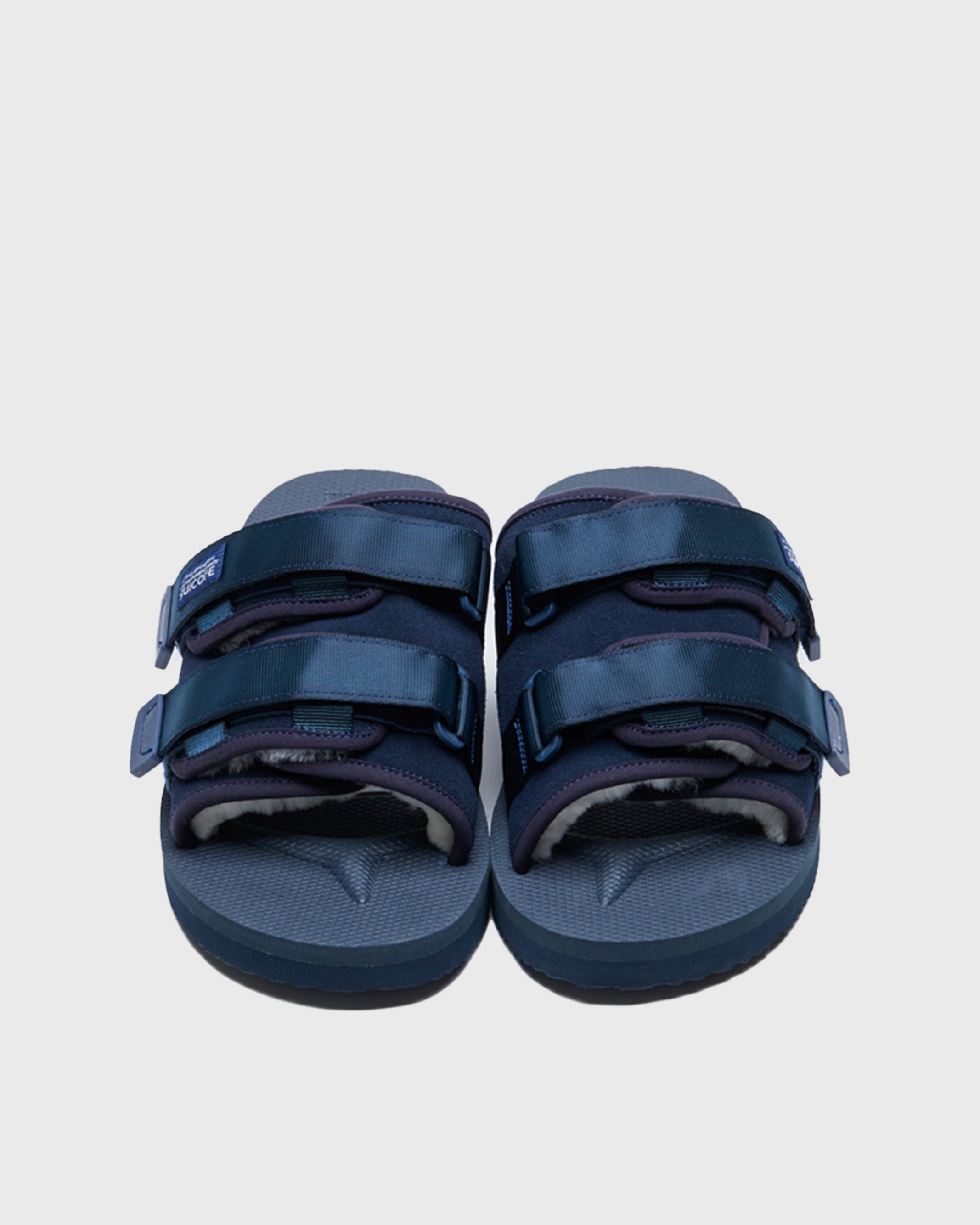 SUICOKE MOTO-Mab suede slides with navy midsole and sole, navy suede upper and shearling inside with navy piping and nylon straps and end tabs, and logo patch. From Fall/Winter 2021 collection on SUICOKE Official US & Canada Webstore.