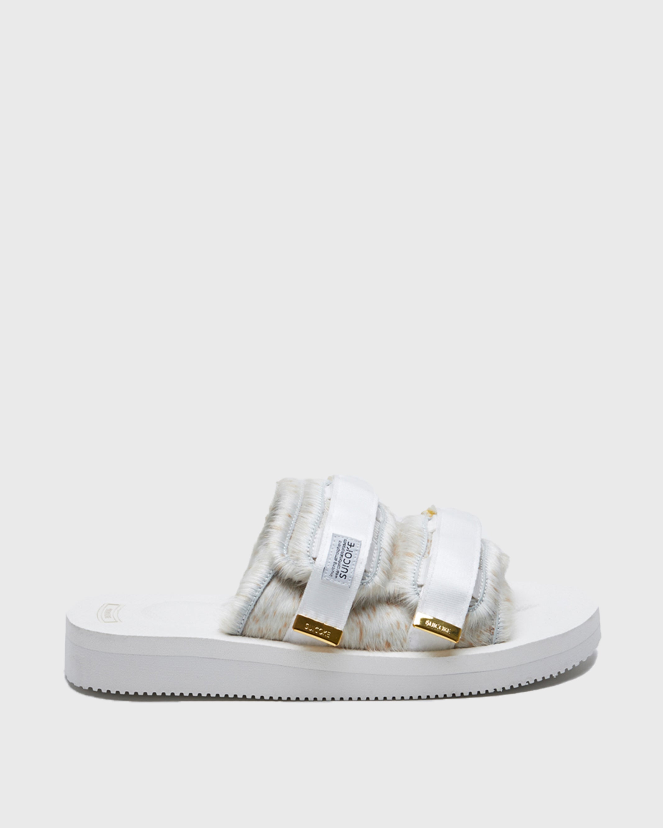 SUICOKE MOTO-Vhl slides with white, brown speckled colored calf hair upper, white midsole and sole, nylon straps with logo patch and gold logoed tabs. From Fall/Winter 2021 collection on SUICOKE Official US & Canada Webstore.