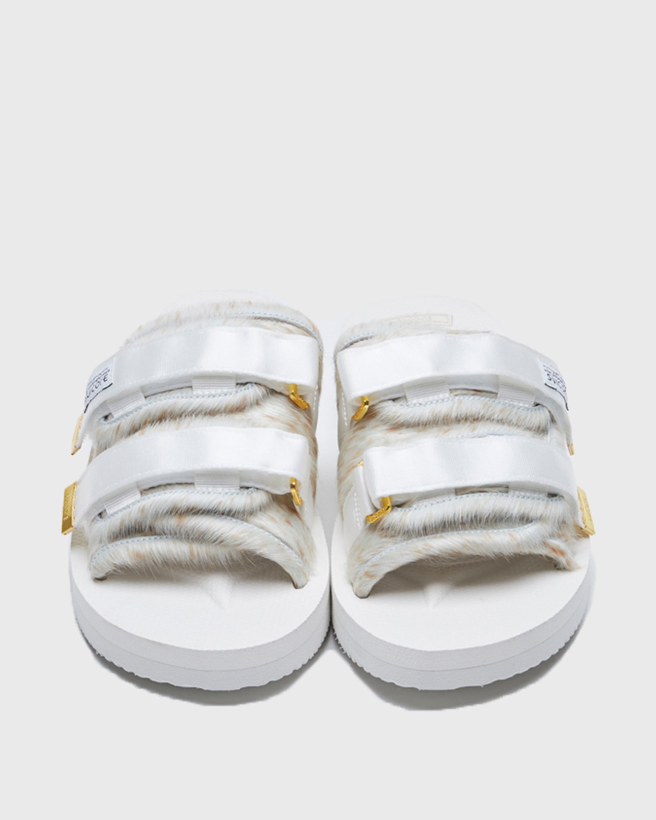 SUICOKE MOTO-Vhl slides with white, brown speckled colored calf hair upper, white midsole and sole, nylon straps with logo patch and gold logoed tabs. From Fall/Winter 2021 collection on SUICOKE Official US & Canada Webstore.