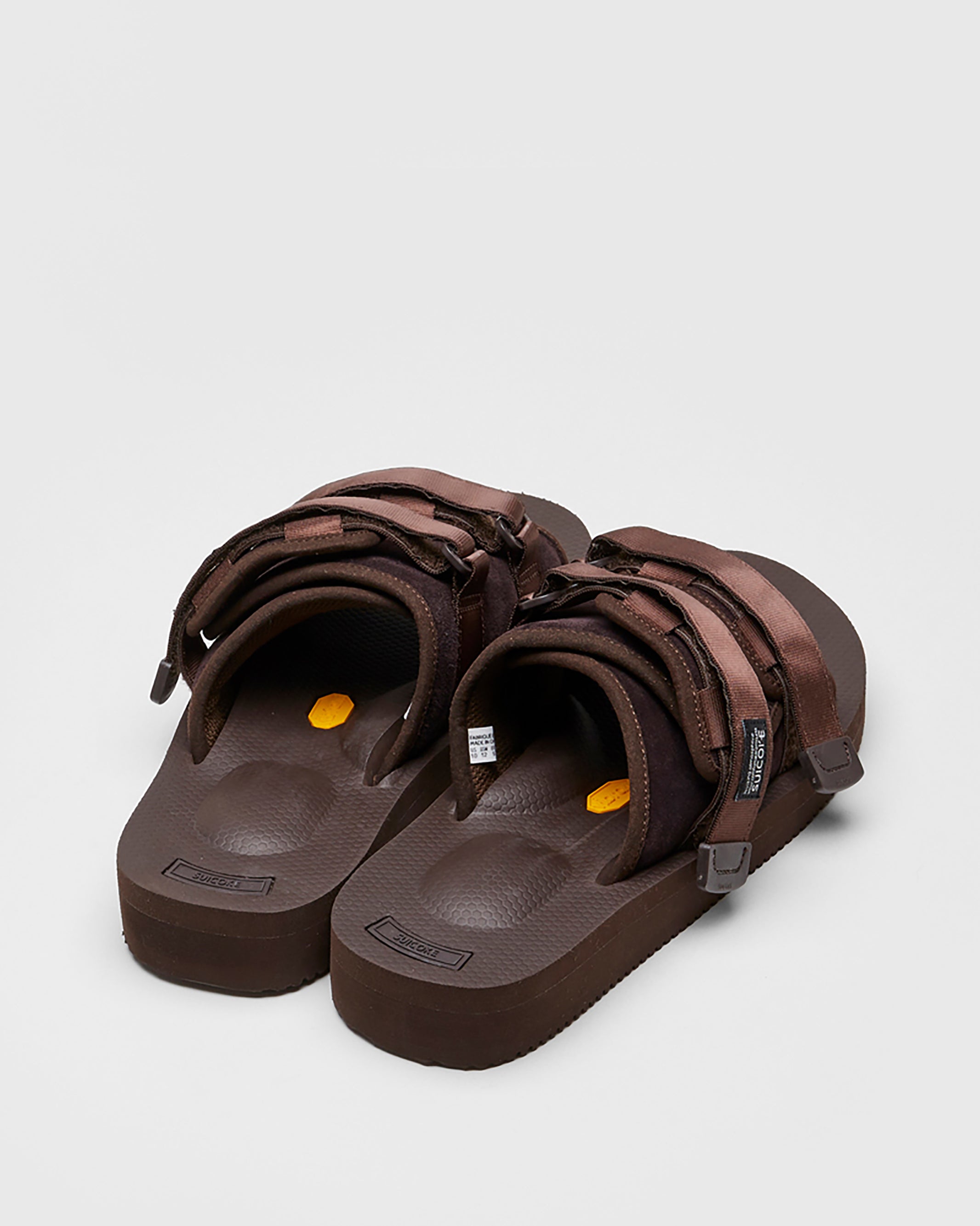 SUICOKE MOTO-VS slides with brown cow suede upper, brown midsole and sole, straps and logo patch. From Spring/Summer 2022 collection on SUICOKE Official US & Canada Webstore.