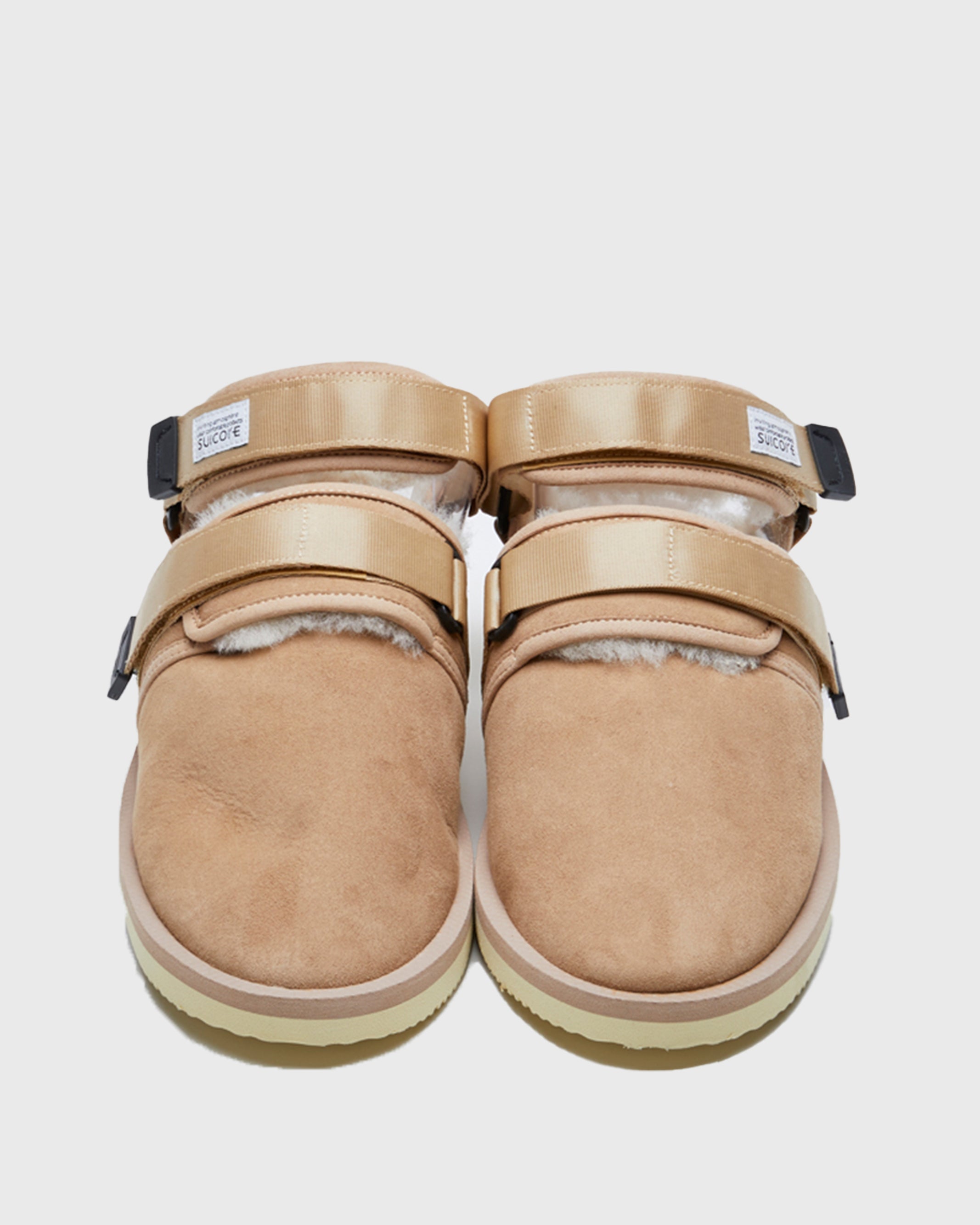 SUICOKE NOTS-M2ab sandals with beige suede upper and midsole and light-yellow sole with shearling inside with beige nylon ankle straps and black tabs with logo patch. Opening between ankle straps and toe upper. From Fall/Winter 2021 collection on SUICOKE Official US & Canada Webstore.