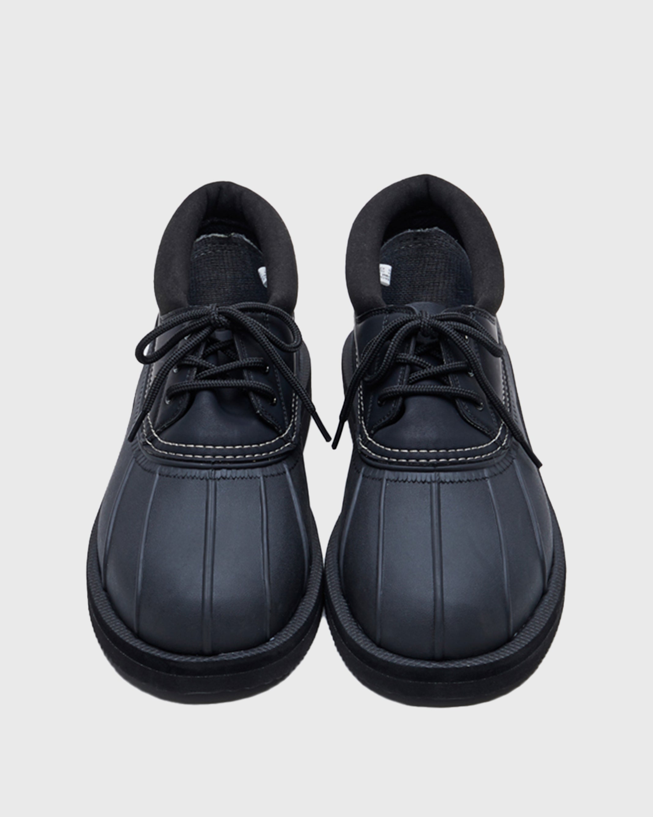 SUICOKE ALAL-Wpab-LO low-top black boot in faux leather upper + rubber duck boot with white contrast stitching. Including black cord laces and pull tab at heel. From Fall/Winter 2021 collection on SUICOKE Official US & Canada Webstore.