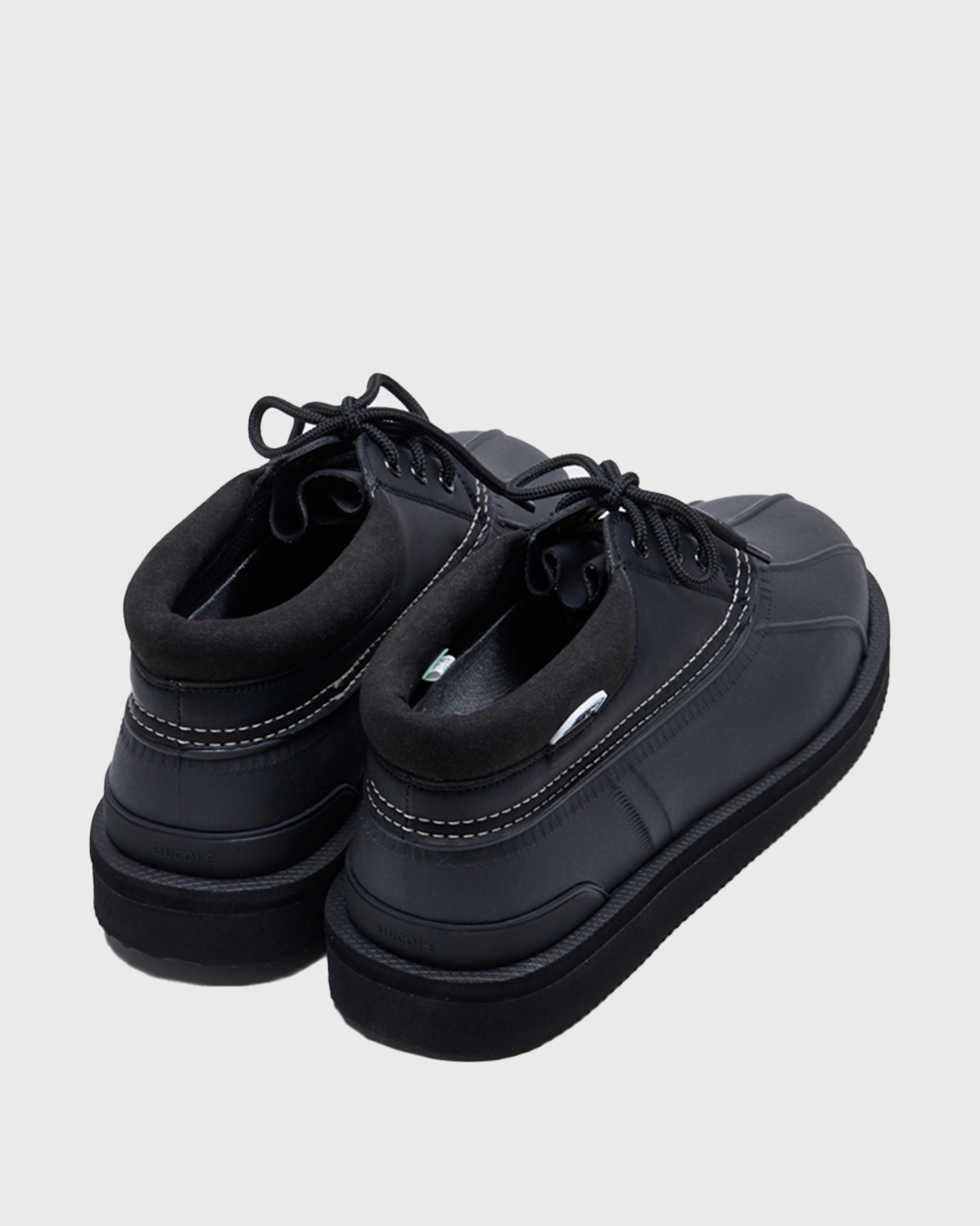 SUICOKE ALAL-Wpab-LO low-top black boot in faux leather upper + rubber duck boot with white contrast stitching. Including black cord laces and pull tab at heel. From Fall/Winter 2021 collection on SUICOKE Official US & Canada Webstore.