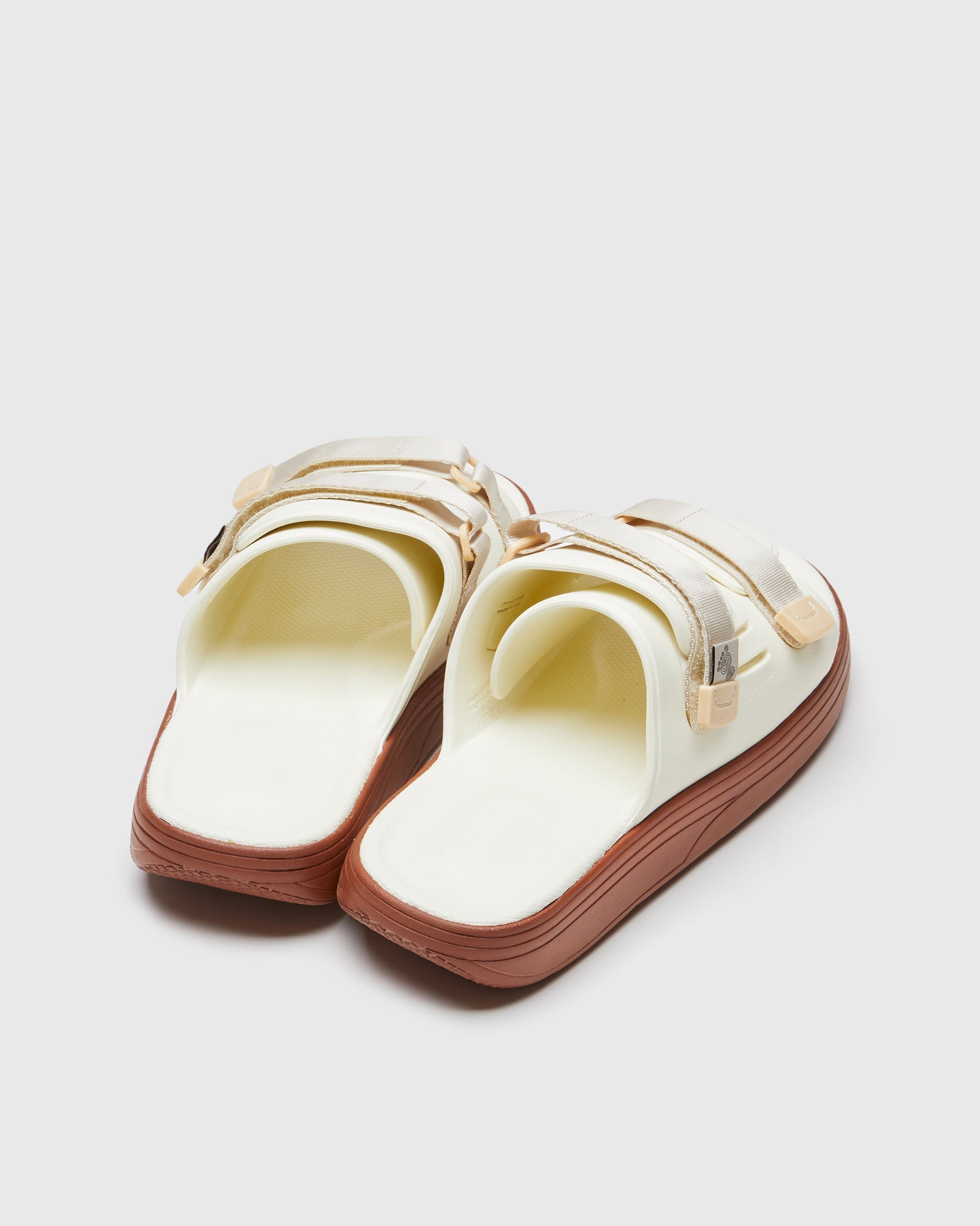 SUICOKE URICH slides with off-white rubber upper, off-white rubber midsole and sole, off white nylon strap and logo patch. From Spring/Summer 2023 collection on SUICOKE Official US & Canada Webstore. OG-INJ-01 OFF WHITE