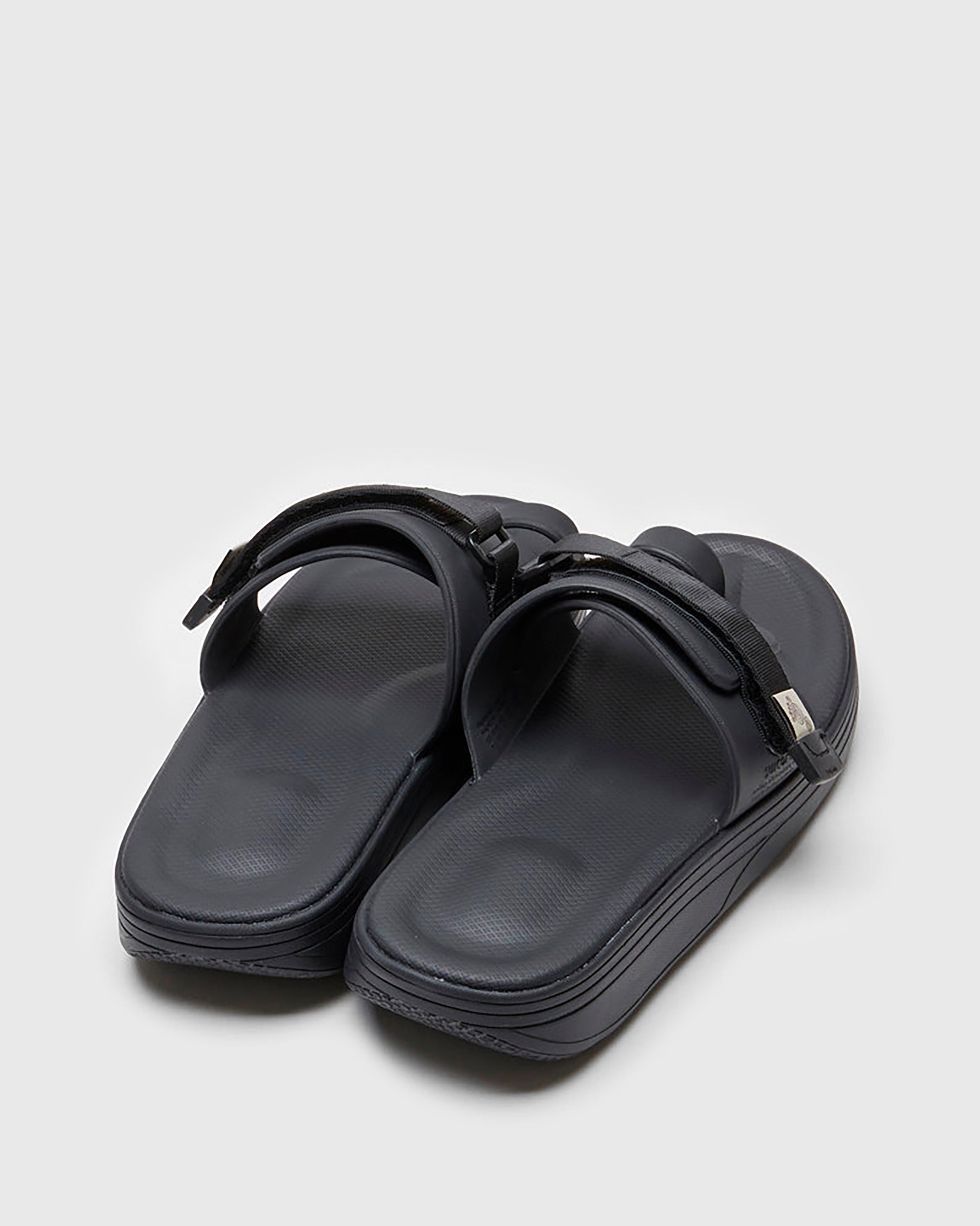 SUICOKE UTA slides with black rubber upper, black midsole and sole, straps and logo patch. From Spring/Summer 2022 collection on SUICOKE Official US & Canada Webstore.