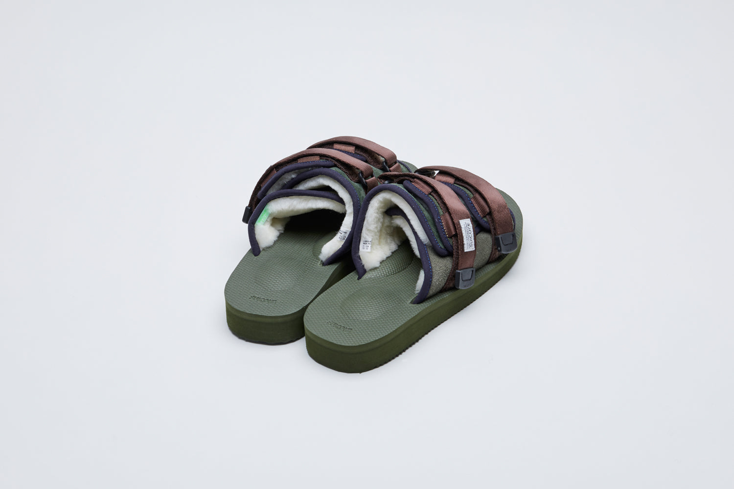 SUICOKE MOTO-Mab suede slides with green midsole and sole, green suede upper and shearling inside with navy piping and brown nylon straps with a logo patch. From Fall/Winter 2021 collection on SUICOKE Official US &amp; Canada Webstore.