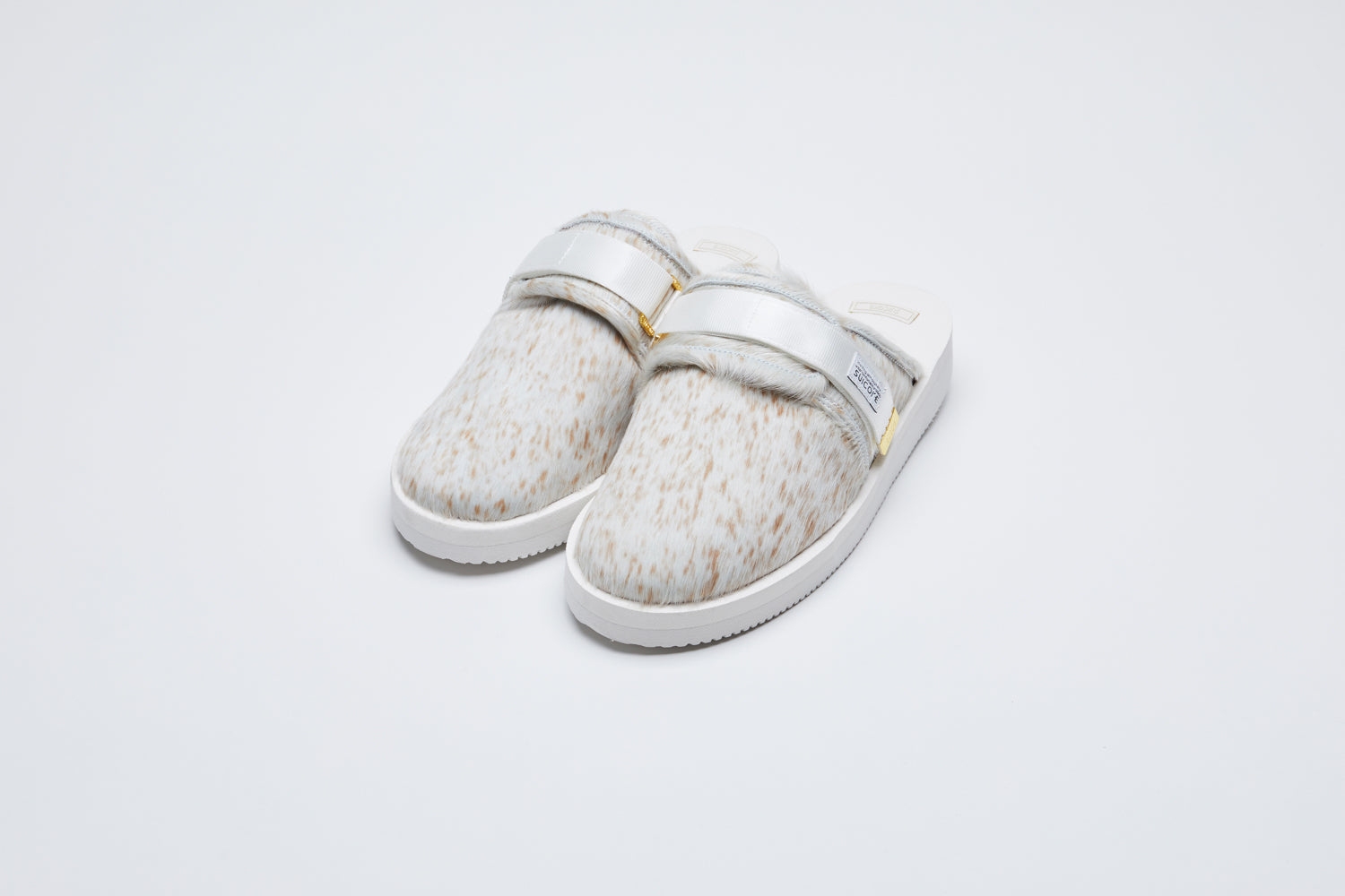 SUICOKE ZAVO-Vhl closed toe slides with white-brown speckled colored calf hair upper, white midsole and sole, nylon straps with logo patch and gold logoed tabs.  From Fall/Winter 2021 collection on SUICOKE Official US & Canada Webstore.