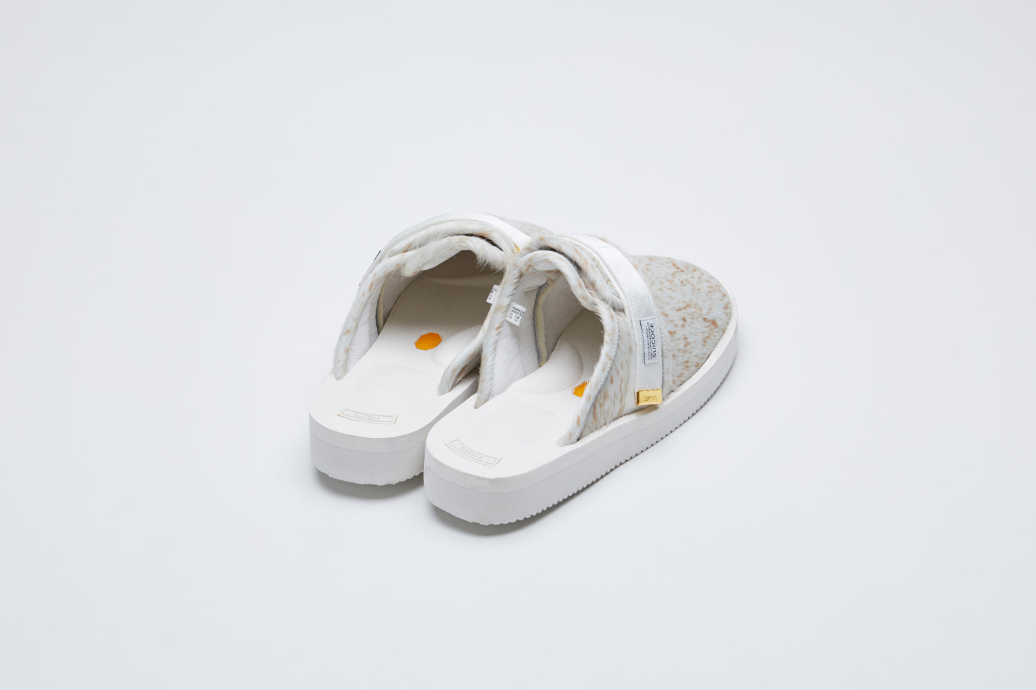 SUICOKE ZAVO-Vhl closed toe slides with white-brown speckled colored calf hair upper, white midsole and sole, nylon straps with logo patch and gold logoed tabs.  From Fall/Winter 2021 collection on SUICOKE Official US & Canada Webstore.