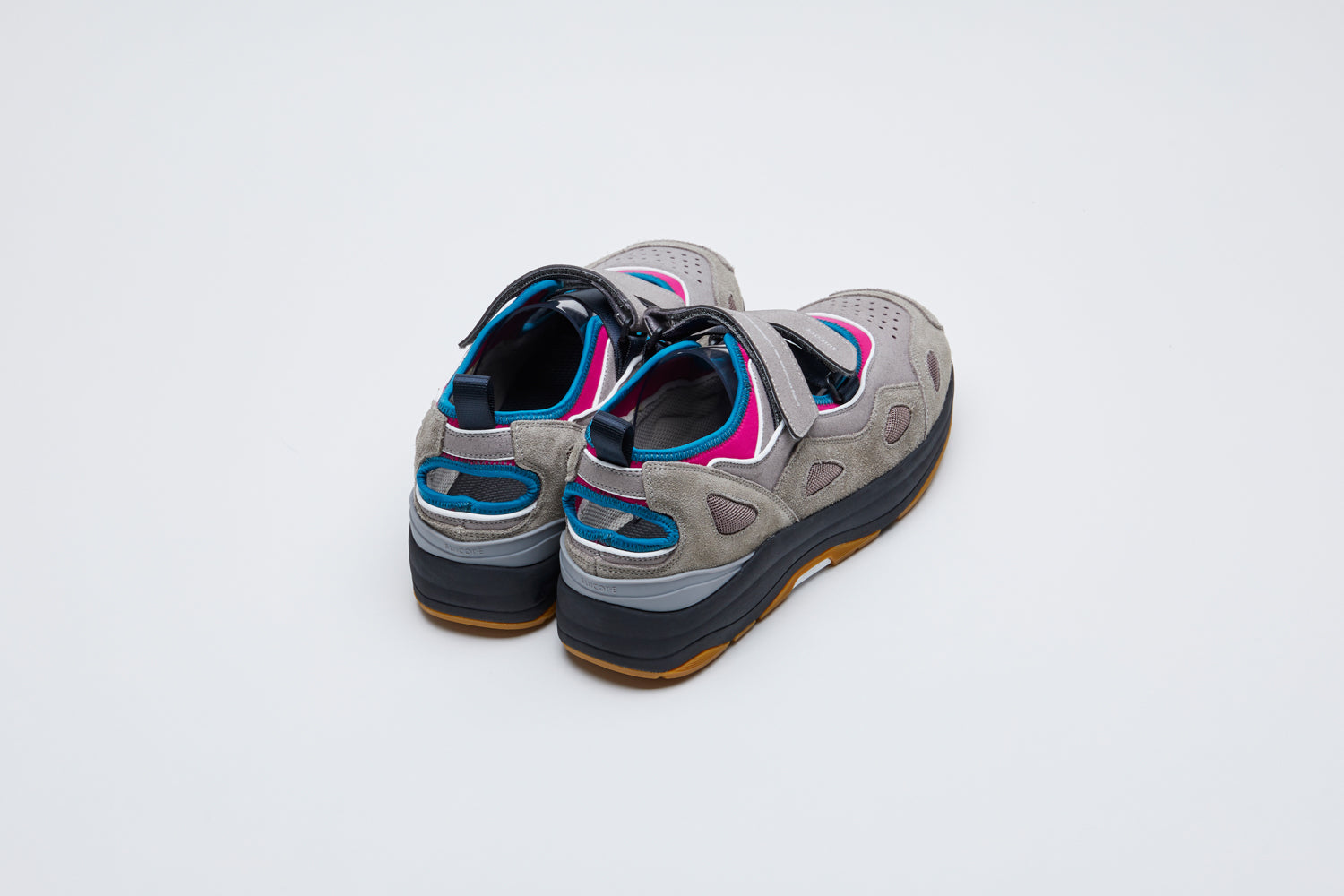 SUICOKE AKK-ab shoe with magenta polyester, navy nylon and gray suede, black rubber running midsole and beige sole. Upper finished with blue piping, gray velcro straps with heel loop. Small openings at heel and top where straps are placed. From Fall/Winter 2021 collection on SUICOKE Official US & Canada Webstore.